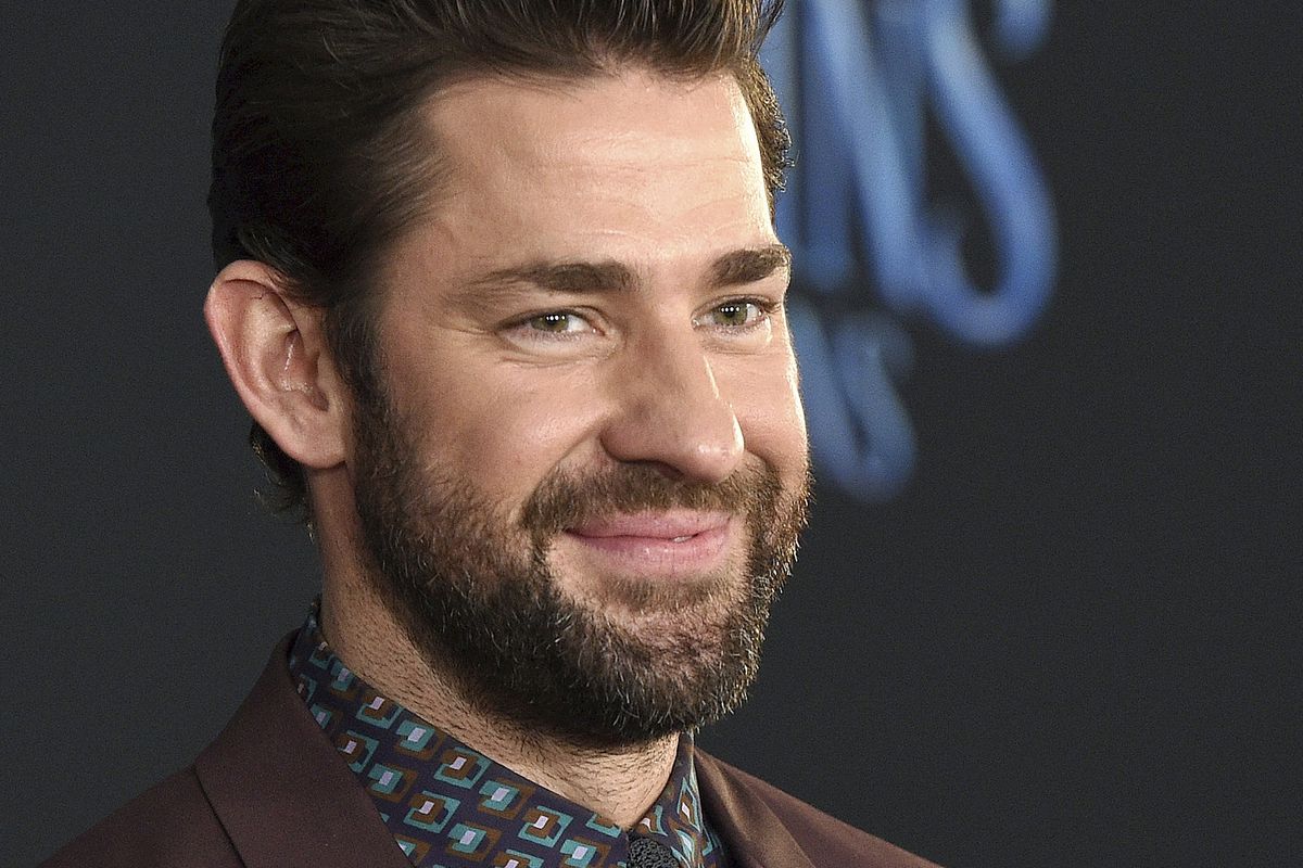 Potret John Krasinski di sebuah acara red carpet, dengan setelan jas maroon